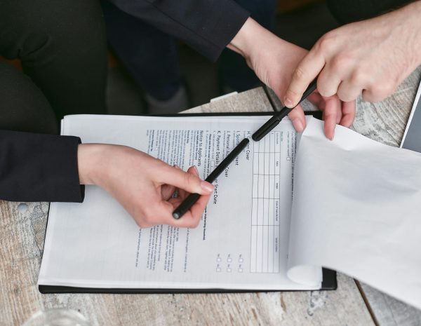 pexels-photo-7735699-7735699 Close-up of business hands finalizing agreement with pen on documents.